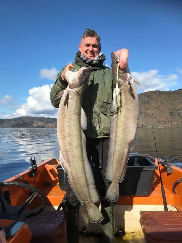 Kunde i båt holder opp to store langer